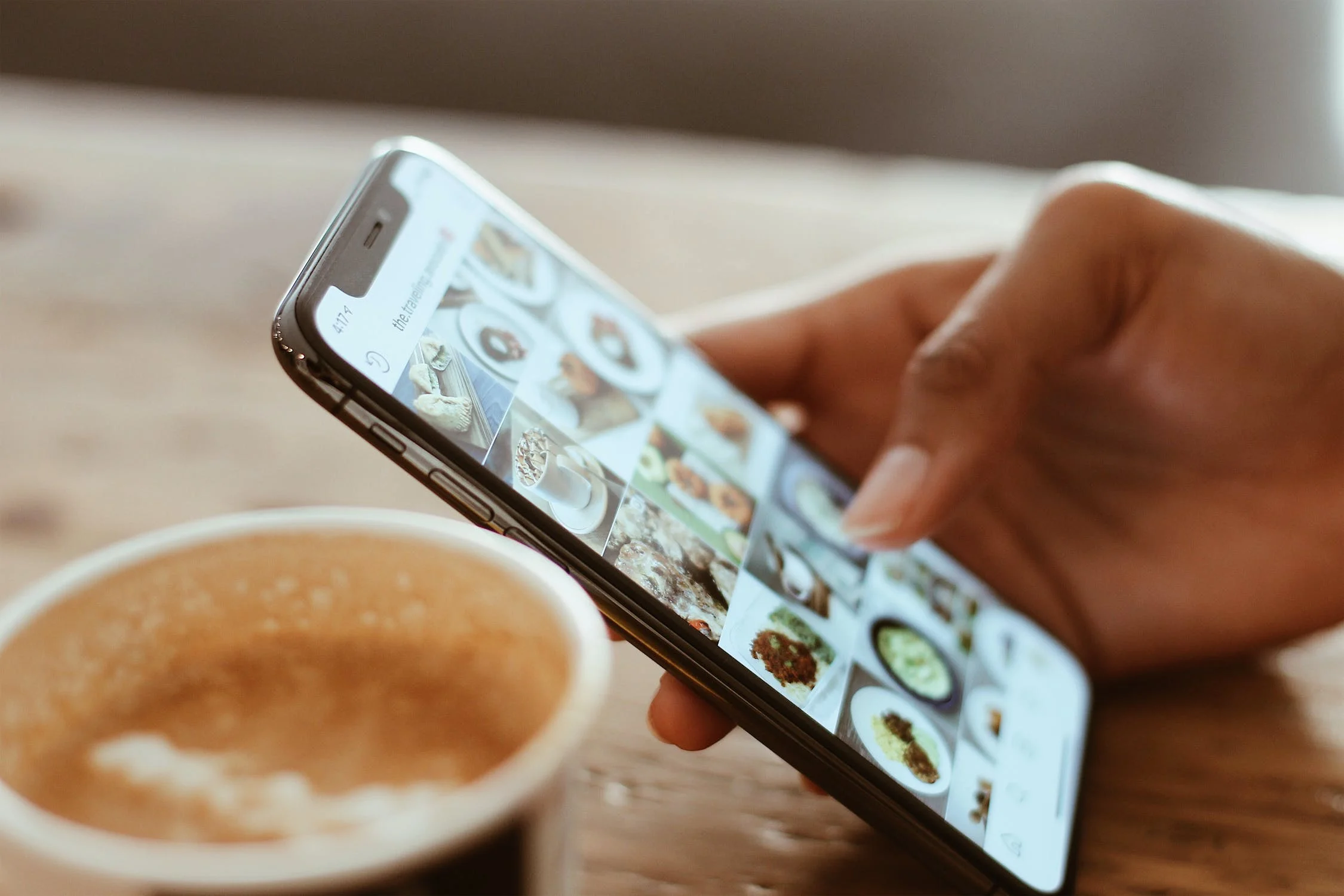 Person browsing phone with coffee