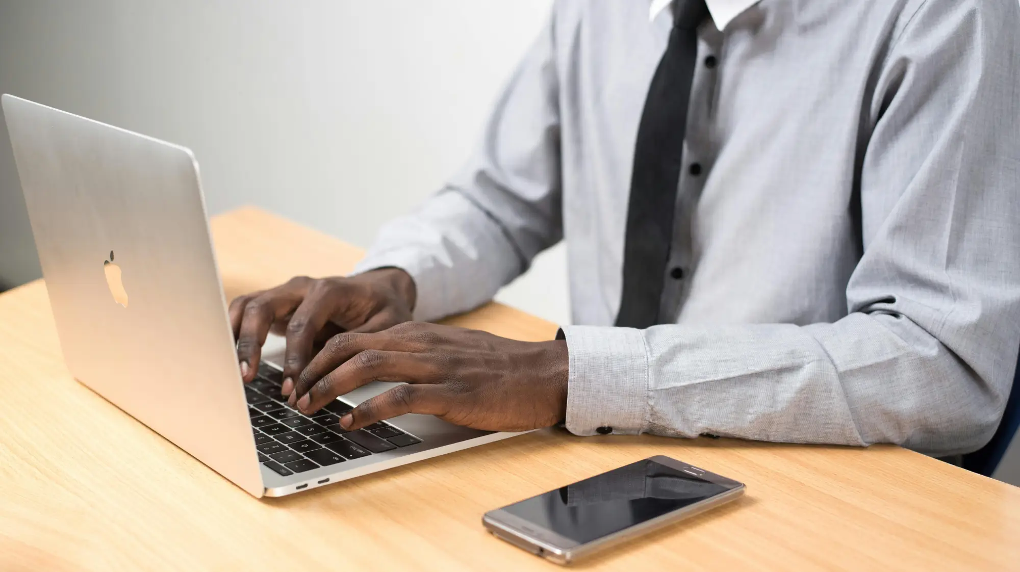 Man typing on laptop with phone nearby